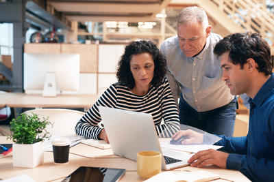 Two male and one female colleague collaborate at a desk