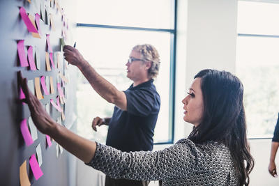 A woman and a man sticking labels onto a strategy board