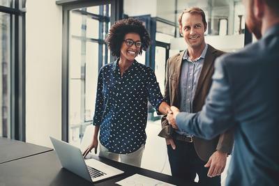 A female candidate shakes hands with her interviewer after being hired