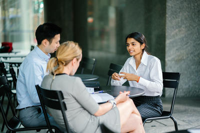 A women in the middle of talking in an interview with a man and a woman around a table