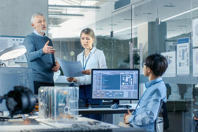 Two women and one man discussing work matters across a desk