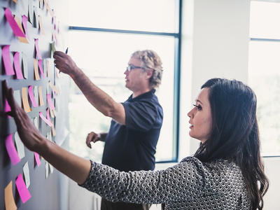 A woman and a man sticking labels onto a strategy board