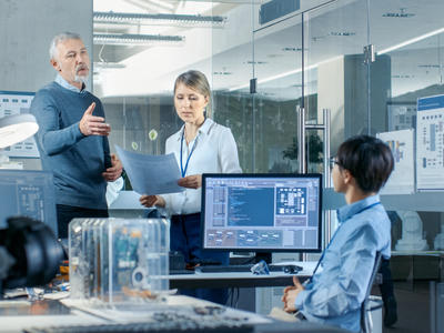 Two women and one man discussing work matters across a desk