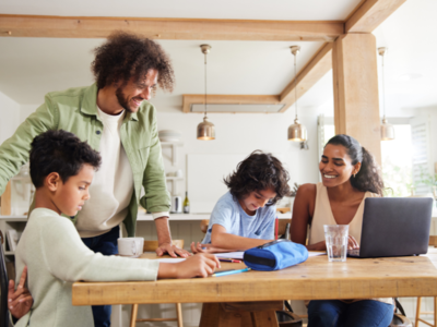 Mother and father at dining table with their two children and a laptop on the desk