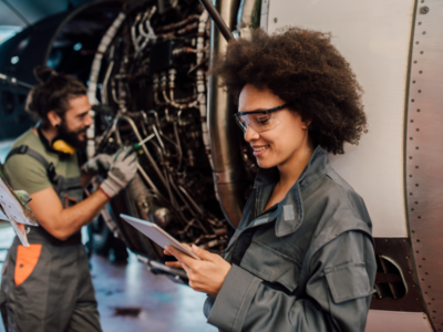 Two people smiling while working on an aeroplane