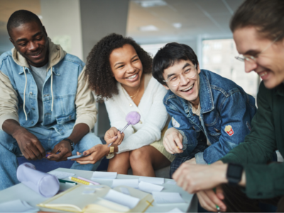 A group of people sitting around a table laughing and smiling