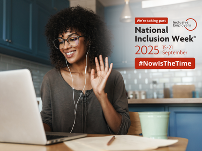 Smiling woman using laptop in kitchen, waving at the camera